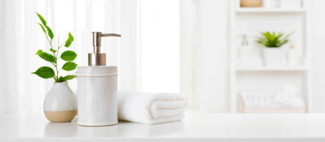 Soap dispenser and spa towel on pastel bathroom window interior